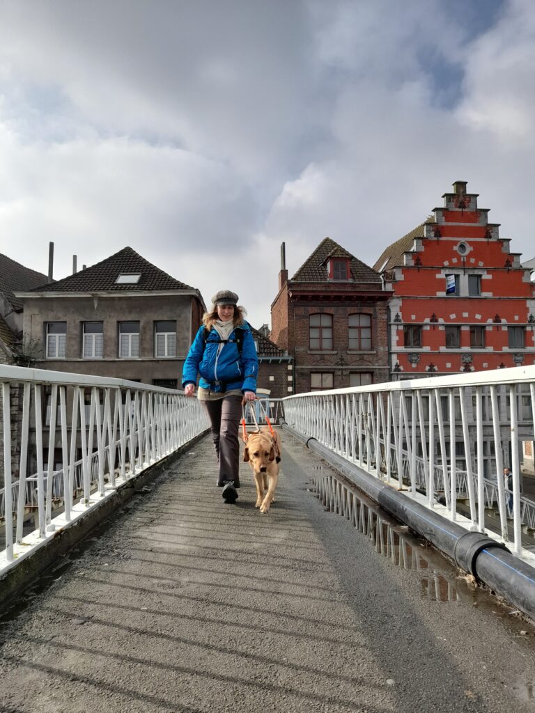 Remise de Skadi - Une dame marche sur un pont avec son labrador sable