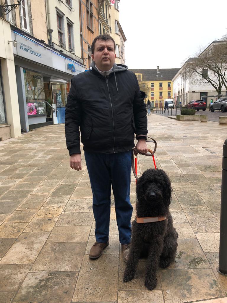 Remise de Sirkis - un monsieur tient sont chien guide un labradoodle noir